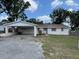 Cozy single-story home featuring a large front yard, a carport, and a classic front door at 37913 Wicklow Ave, Zephyrhills, FL 33541