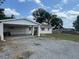 Single-story home featuring a front yard, a carport with a motorcycle, and classic detailing at 37913 Wicklow Ave, Zephyrhills, FL 33541