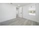 An empty bedroom featuring light gray wood-style flooring, a window, and white trim at 6504 N 13Th St, Tampa, FL 33604