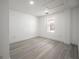 An empty bedroom featuring light gray wood-style flooring, a window, and white trim at 6504 N 13Th St, Tampa, FL 33604