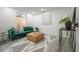 Living room featuring emerald green couch, leather ottoman, black and white rug and white walls at 6504 N 13Th St, Tampa, FL 33604