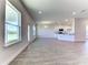 Spacious, open-concept living room with wood-look tile flooring, large windows, and access to the kitchen at 6807 162Nd Pl, Parrish, FL 34219
