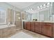 Bright bathroom featuring a bathtub, glass door shower, and double vanity sink with great lighting at 7710 S Desoto St, Tampa, FL 33616