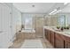 Bright bathroom featuring a bathtub, glass door shower, and double vanity sink with good lighting at 7710 S Desoto St, Tampa, FL 33616