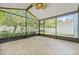 Spacious screened lanai with tile flooring, ceiling fan, and views of the landscaped backyard and white fence at 7710 S Desoto St, Tampa, FL 33616