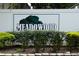 Close up of Meadowood Condominiums sign, landscaped with neatly trimmed bushes at 8011 Peach Dr # 103, Tampa, FL 33637
