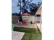 Outdoor patio with a table, chairs, and umbrella surrounded by artificial grass, offering space for relaxing and dining at 8129 23Rd N Ave, St Petersburg, FL 33710