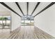 Open living space with beams, wood-look floors, and view to the pool through large windows at 8413 Lopez Dr, Tampa, FL 33615