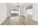 Open-concept living room with wood-look floors, modern chandelier, and sliding doors to pool area at 8413 Lopez Dr, Tampa, FL 33615