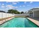 A beautiful rectangular in-ground swimming pool and patio bordered by a white fence and screened patio area at 8413 Lopez Dr, Tampa, FL 33615