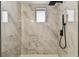 A renovated shower stall with marbled tile and a window, along with a modern black shower head at 8413 Lopez Dr, Tampa, FL 33615