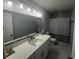 Updated bathroom with white vanity, large mirror with lights, and tile shower at 8423 Edgewater Place Blvd, Tampa, FL 33615