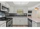 Kitchen with stainless steel appliances, white cabinetry, and sleek backsplash; view to open floorplan living area at 9107 Spring Hill Dr, Spring Hill, FL 34608