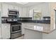Kitchen with stainless steel appliances, white cabinetry and sleek backsplash, filled with natural light at 9107 Spring Hill Dr, Spring Hill, FL 34608