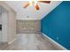 Spacious living room with wood-look flooring, a ceiling fan, and a bold blue accent wall at 9107 Spring Hill Dr, Spring Hill, FL 34608