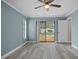 Bright main bedroom with light blue walls, light wood flooring, a ceiling fan, and sliding doors to the screened pool area at 9107 Spring Hill Dr, Spring Hill, FL 34608