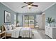 Bright main bedroom with light blue walls, light wood flooring, a ceiling fan, and a sliding glass door to the backyard pool at 9107 Spring Hill Dr, Spring Hill, FL 34608