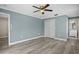Spacious main bedroom with light wood flooring, light blue walls, a ceiling fan, closet, and an ensuite bathroom at 9107 Spring Hill Dr, Spring Hill, FL 34608