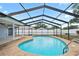 Sparkling pool with screened enclosure, concrete decking, and meticulously maintained landscaping at 9107 Spring Hill Dr, Spring Hill, FL 34608