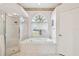 Bathroom with a large garden tub under a window and a separate glass door shower at 9219 Irondale Ln, Hudson, FL 34667