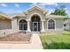 Inviting front entrance with arched windows, decorative glass door, and well-maintained landscaping at 9219 Irondale Ln, Hudson, FL 34667