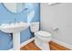 Updated bathroom features a pedestal sink, toilet, blue wall, and hardwood floors at 113 E Bosphorous Ave # 5, Tampa, FL 33606