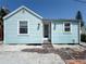 Charming light-blue home featuring a brick path, two windows, and a white front door at 13326 1St E St, Madeira Beach, FL 33708