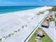 Aerial view of pristine white sand beach, tiki huts, and turquoise waters by condo at 1400 Gulf Blvd # 804, Clearwater Beach, FL 33767