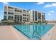 Outdoor pool at beachfront condo featuring lounge chairs, clear skies, and lush landscaping at 1400 Gulf Blvd # 804, Clearwater Beach, FL 33767