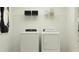 Efficient laundry room with modern washer and dryer, complemented by a shelf for storage, perfect for household needs at 15045 Zircon Red Dr, Wimauma, FL 33598