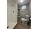 Bathroom with white tiled shower, new toilet, small sink with shelves, and modern laminate floor at 1536 S Martin Luther King Jr Ave, Clearwater, FL 33756