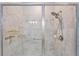 A glass enclosed shower featuring a multi-setting shower head, and gold toned hardware and storage at 16866 Balance Cv, Land O Lakes, FL 34638
