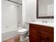 Bathroom with a white tiled tub and shower, a wooden vanity and mirror at 1936 Heron Cove Dr # 104, Lutz, FL 33549
