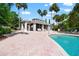 Community pool area with brick-paved patio, lounge chairs, and a building with covered seating at 1936 Heron Cove Dr # 104, Lutz, FL 33549