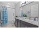 Modern bathroom featuring double sinks, granite countertops and stylish blue shower curtain at 21642 Emory Oak Pl, Land O Lakes, FL 34637