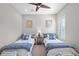 Bright bedroom featuring two beds with patterned bedding, a ceiling fan, and neutral color scheme for a relaxing ambiance at 21642 Emory Oak Pl, Land O Lakes, FL 34637