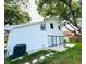 The home's back exterior has a white facade with sliding glass doors and a lush green yard at 2233 Springwood W Cir, Clearwater, FL 33763