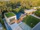 An aerial view showcases a modern home's rooftop deck, geometric driveway, and proximity to lush surroundings at 3165 Renatta Dr, Belleair Bluffs, FL 33770