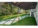 Serene backyard features lush landscaping and a decorative walkway from the covered patio at 3165 Renatta Dr, Belleair Bluffs, FL 33770