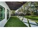 Beautiful backyard and patio area boasts artificial turf, decorative stone walkway, and mature trees at 3165 Renatta Dr, Belleair Bluffs, FL 33770