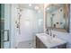 Modern bathroom with glass-enclosed shower featuring herringbone tile and a vanity with a marble countertop at 3165 Renatta Dr, Belleair Bluffs, FL 33770