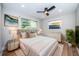 Bright bedroom featuring a plush bed, ceiling fan, hardwood floors, and ample natural light from two windows at 3165 Renatta Dr, Belleair Bluffs, FL 33770