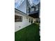 Modern two-story home with balcony access via spiral staircase, artificial turf, and patio cover at 3165 Renatta Dr, Belleair Bluffs, FL 33770