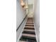 Modern staircase featuring sleek black and wood treads, complemented by a black handrail and sconce lighting at 3165 Renatta Dr, Belleair Bluffs, FL 33770