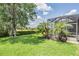 Beautiful backyard featuring green grass, mature trees, and a screened-in patio area for outdoor enjoyment at 32242 Summerglade Dr, Wesley Chapel, FL 33545