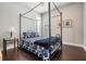 Stylish bedroom features a four-poster bed with patterned bedding and dark hardwood floors at 32242 Summerglade Dr, Wesley Chapel, FL 33545