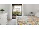 Bright bedroom featuring a bed with floral bedding and a view of the outdoor patio space at 3366 Mermoor Dr # 1106, Palm Harbor, FL 34685