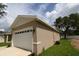 A two-car garage with a white door framed in stucco and green grass and a blue sky at 36777 Thomas Jefferson Rd, Dade City, FL 33525