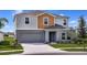 Two-story home with gray stucco, matching garage door, well-manicured lawn, and tasteful landscaping at 37017 Sagemoor Dr, Zephyrhills, FL 33541