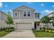 Charming two-story home featuring a two-car garage, well-maintained lawn, and colorful landscaping under a beautiful sky at 37122 Sagemoor Dr, Zephyrhills, FL 33541